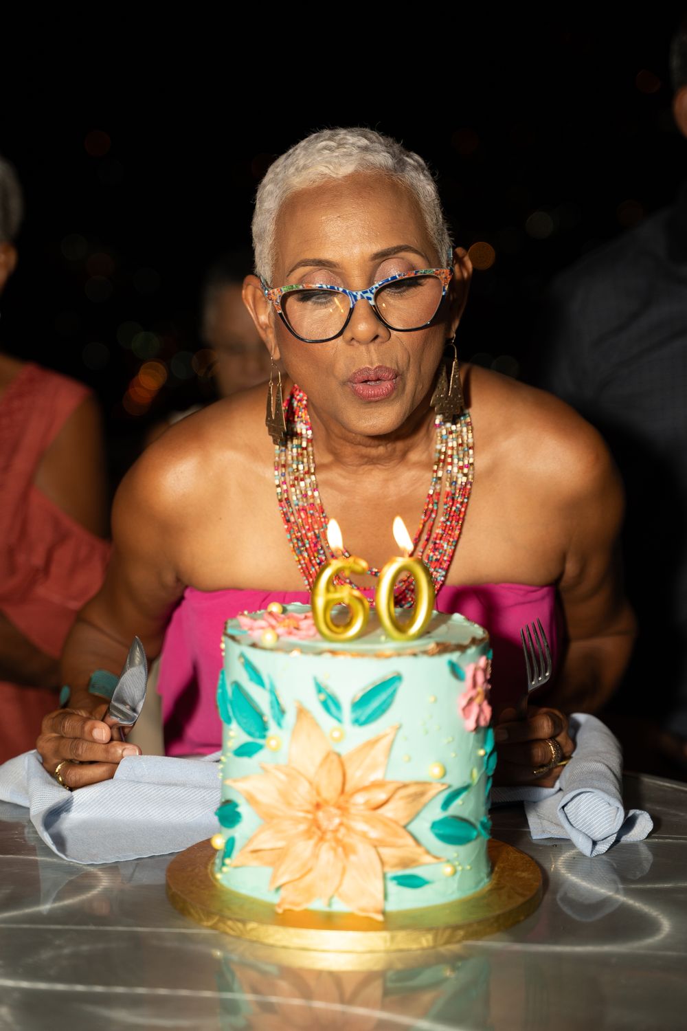 Guest of honor blowing out candles at a 60th birthday celebration