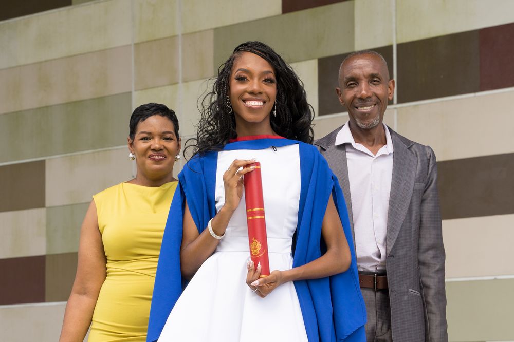 Graduate celebrating with family, holding her diploma