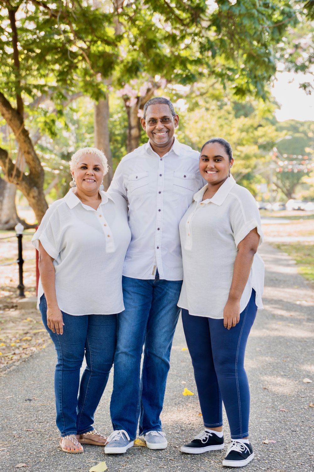 Family portrait of parents and daughter under mossy trees