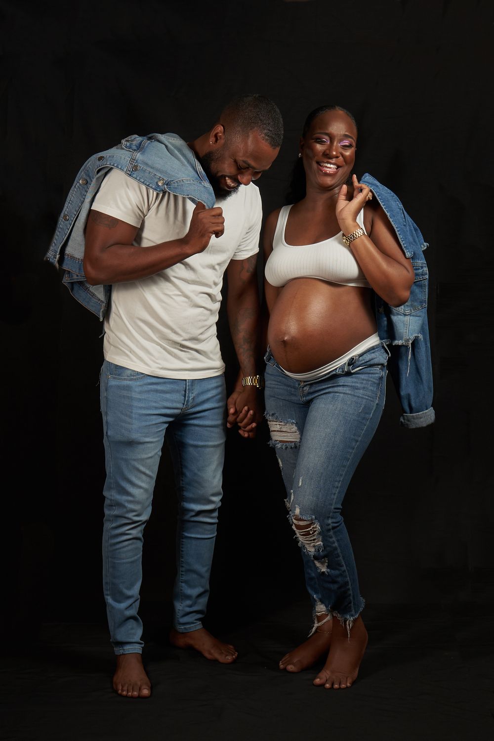 Expecting couple in casual denim, smiling together