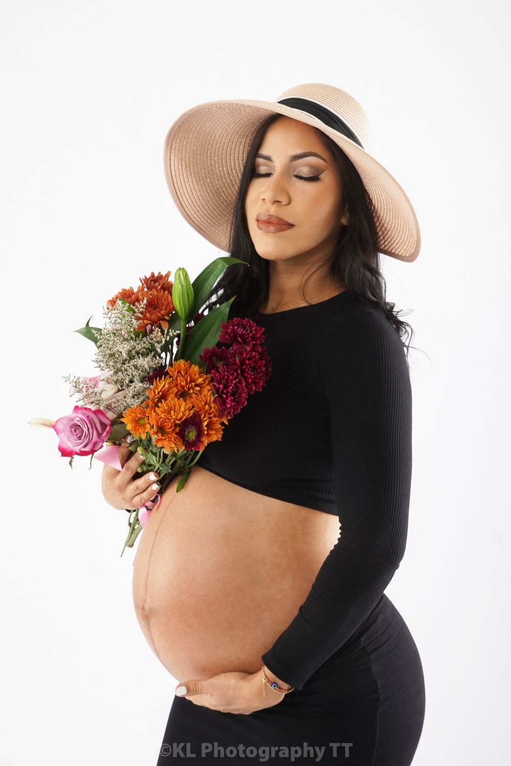 Maternity portrait with a sun hat and bouquet of flowers