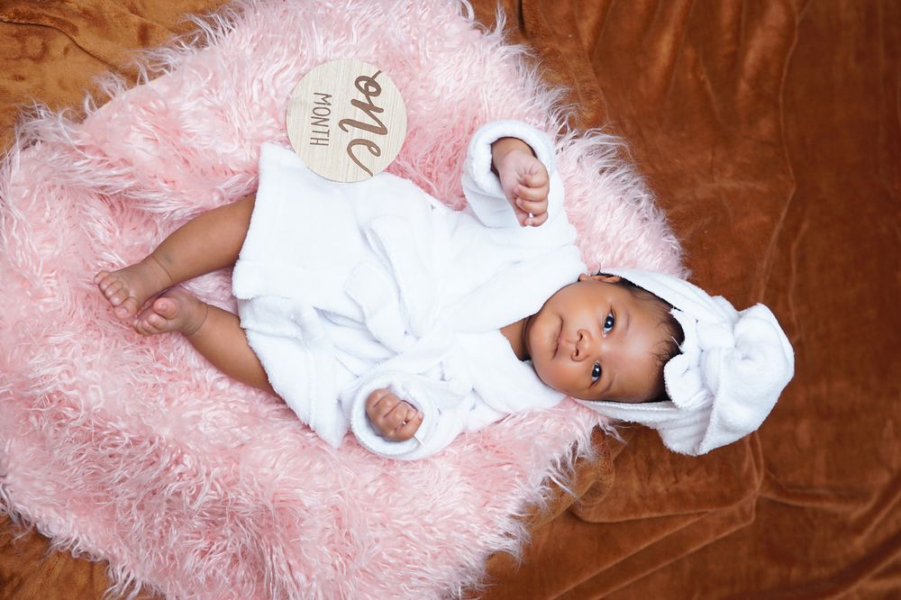 One month old newborn portrait in a white robe
