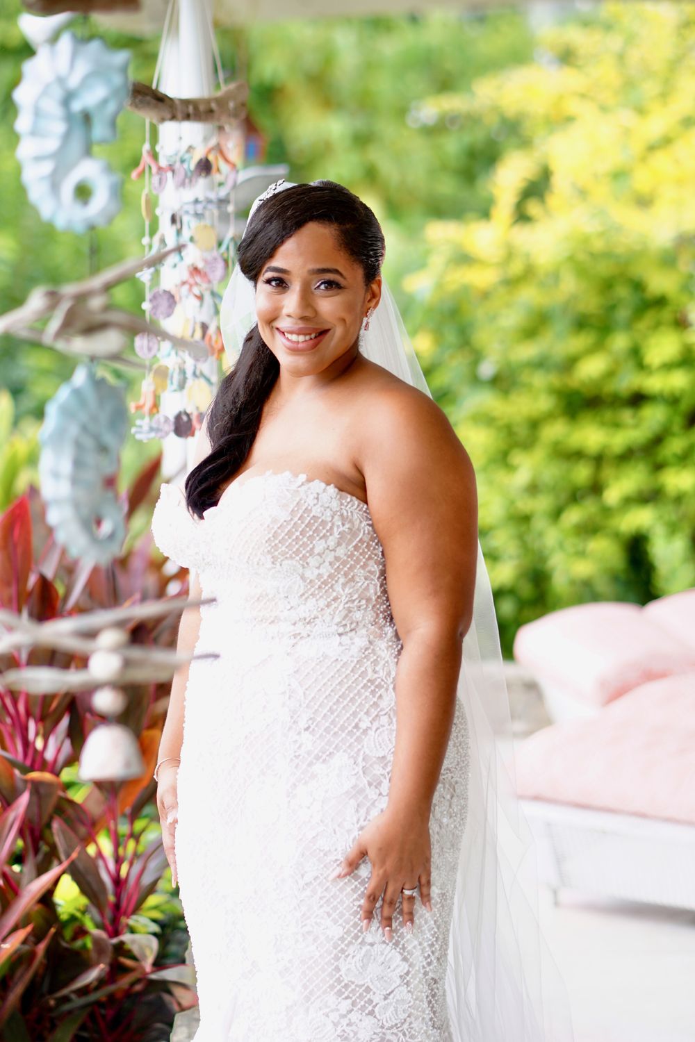 Bride in a lace gown smiling in a garden setting