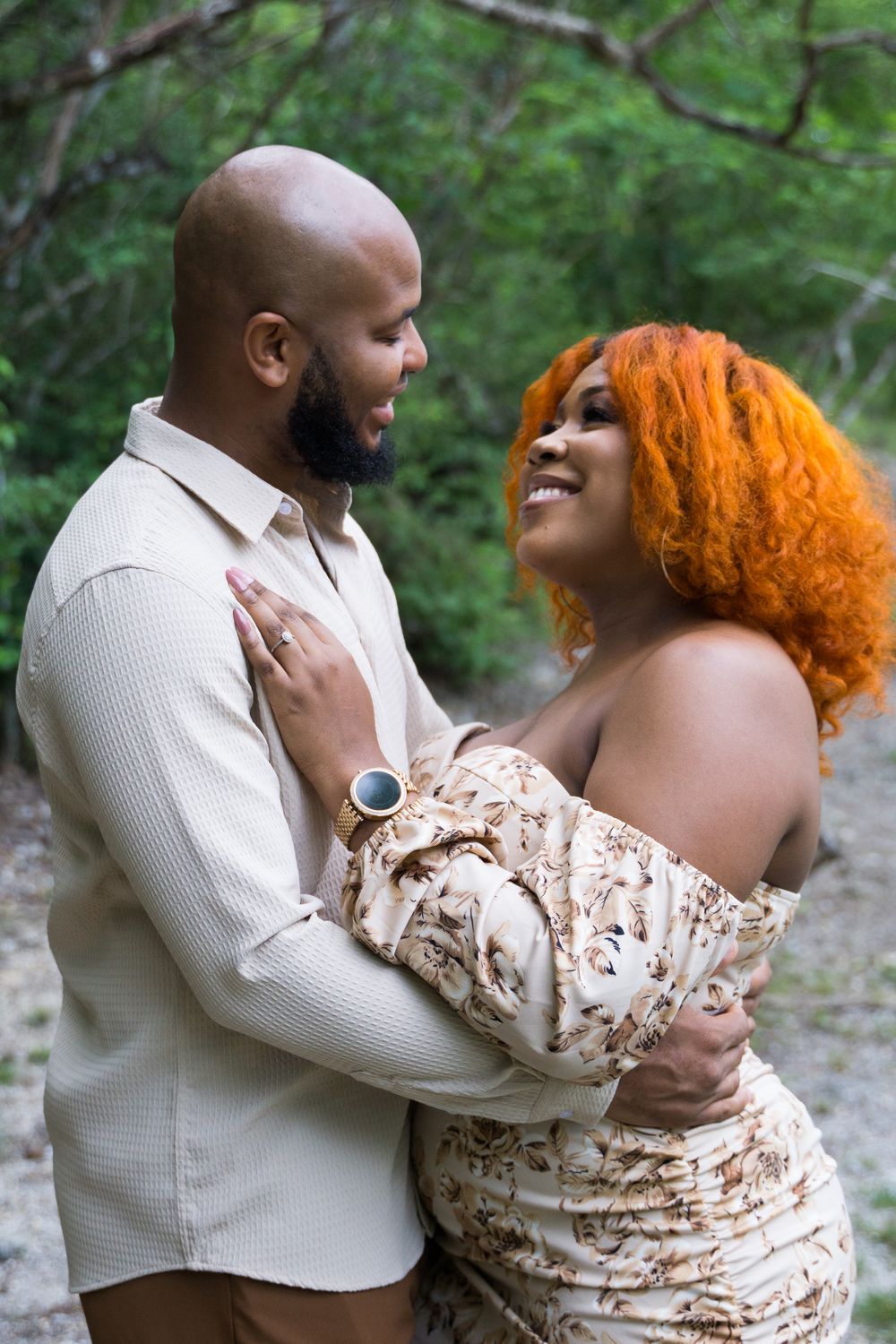 Engaged couple embracing outdoors among greenery