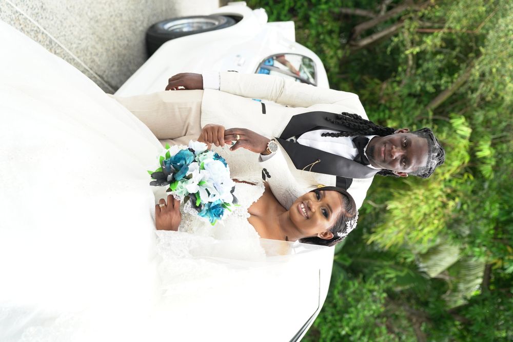 Newlyweds posing beside a vintage white wedding car