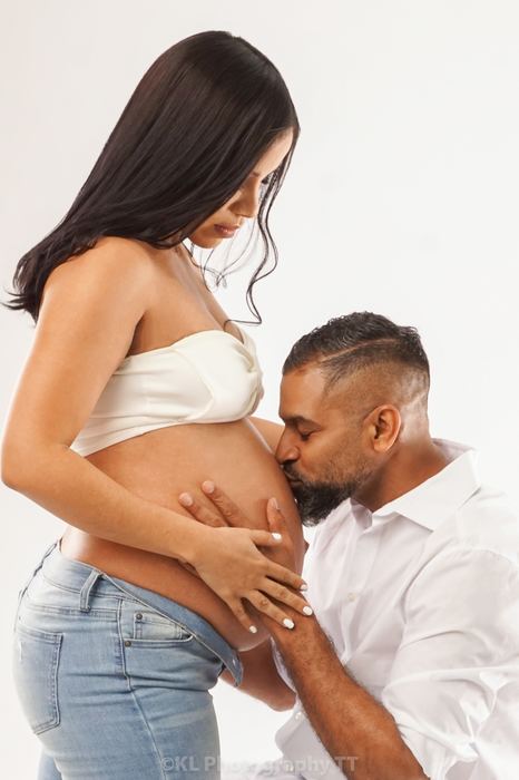 Expecting parents embracing, father kissing the baby bump